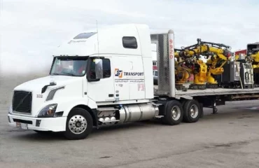 Heavy machinery loaded on ET Motor Freight flatbed.